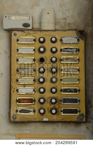 Old weathered doorbell panel in apartment building. Grungy door bell buzzer with broken buttons.