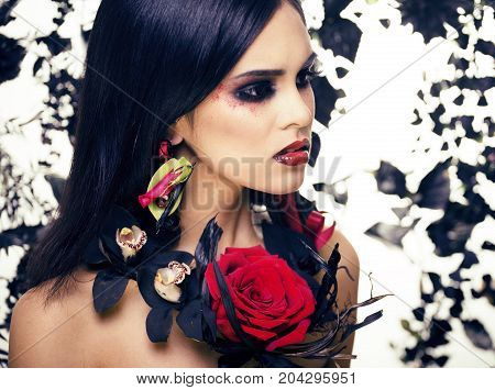 pretty brunette woman with rose jewelry, black and red, bright make up kike a vampire closeup red lips, halloween concept