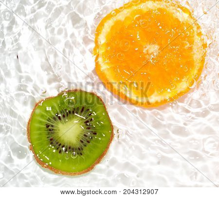 juicy kiwi and orange in water on a white background. macro
