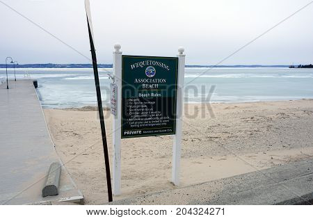 WEQUETONSING, MICHIGAN / UNITED STATES - MARCH 30, 2017: A sign provides the beach rules of the Wequetonsing Association Beach.