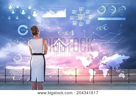 Back view of young businesswoman standing on rooftop with abstract business charts and diagrams on city and sky background. Future and ecnomy concept. Double exposure