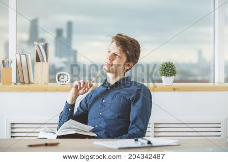 Young Man Reading Book In Office