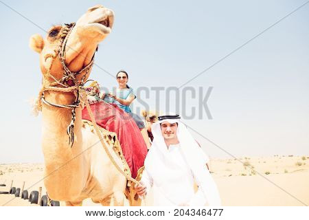 an arabian man and a tourist riding a camel
