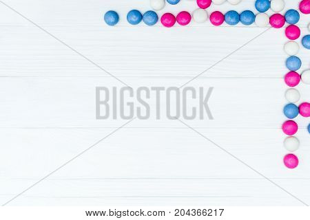 Frame from colorful mint coated candies texture on white wooden background. Top view. Copy space