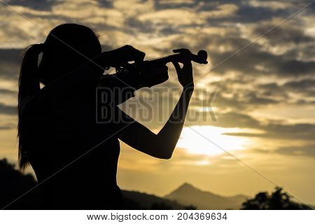 silhouette Violin woman player on sunset background
