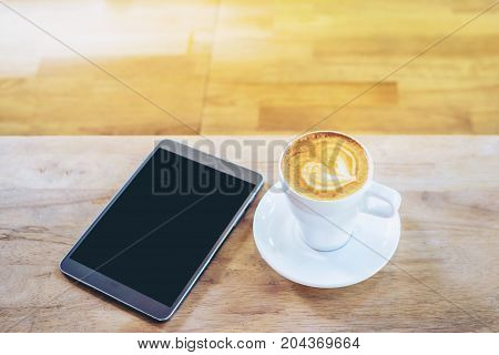 Hot art coffee cappuccino in a cup and smartphone on wooden table background