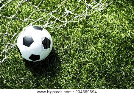 Soccer ball in goal net with green background