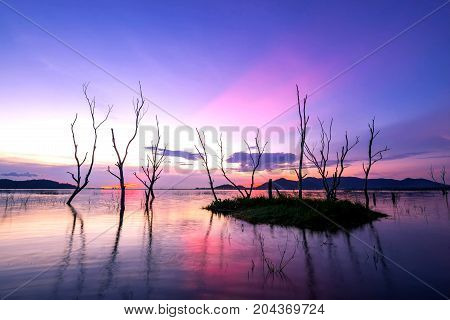 beautiful sunset on the reservoir reflection of silhouettes dry tree landscape thailand