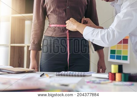 Stylish fashion designer working with measure customer size as sketches in Draft book of new collection in art profession and job occupation Creative Design and Artistic Concept.