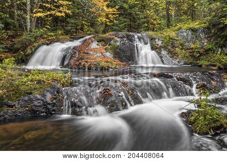 Lower Duppy Falls flows over leaf-covered volcanic rocks in a beautiful remote autumn wood of Michigan's western Upper Peninsula.