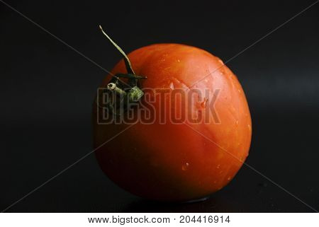 Red fresh ripe tomato in a black background