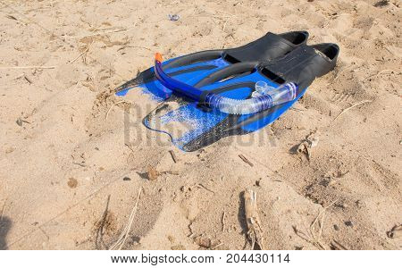 swimming snorkel and fins lying on the sand