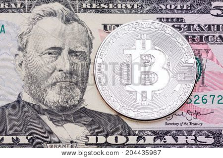 SIlver bitcoin on fifty dollas banknote. High resolution photo.