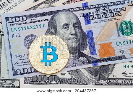 Yellow blue bitcoin on hundred banknotes background. High resolution photo.
