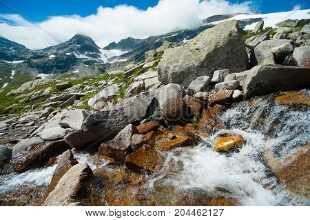 alps landscape wild stream infront of mountains and blue sky