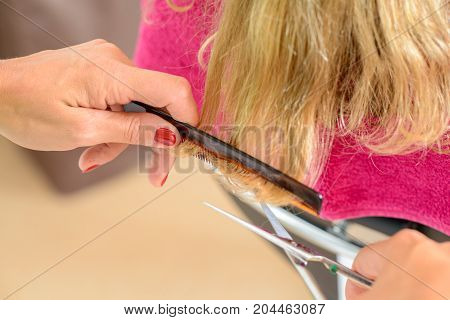 female hairdresser cutting blond hair - close up