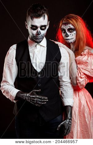 A classy couple, wearing skull make-up for. All souls day. Boy and girl in costumes of skeletons and sugar skull makeup