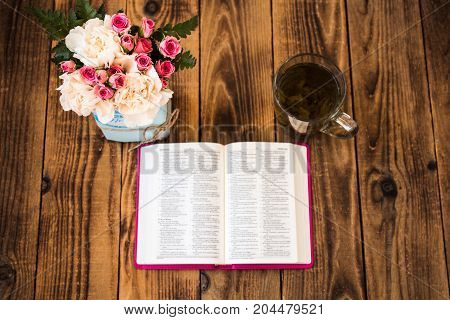 roses tea and bible on a wooden background