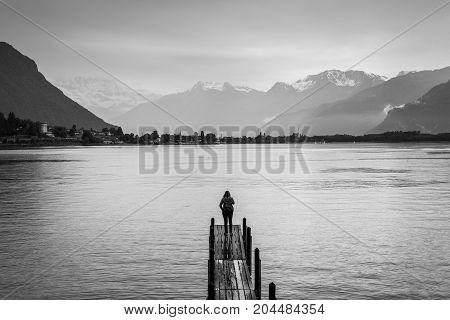 Montreux Switzerland - May 25 2016: Travel woman standing on the wood bridge on the background of the Swiss Lake in Montreux in rainy weather. Black and white photography.