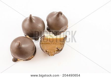 Cones stuffed with sweet or caramel and bathed in whole chocolate and one cut in half. White background.