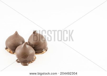 Three cones of dulce de leche or syrup bathed in dark chocolate. Cake shop. White background.