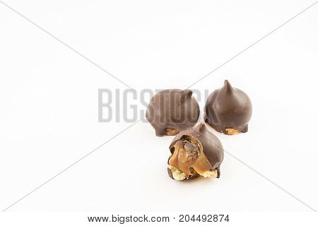 Three cones of dulce de leche bathed in chocolate and one bitten. White background.