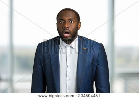 Afro american businessman surprised. Young black CEO manager opened mouth with astonishment. Astonished black man on blurred background.