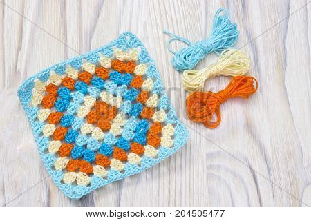 Crochet handmade granny square yarn balls. The beginning of bright plaid blanket. Colorful original knitted handmade work. Homemade creative crochet pattern. Crochet stitches. Rustic background