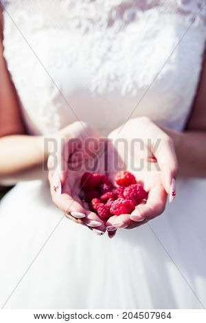 Girl bride holding raspberries in hands summer time joy