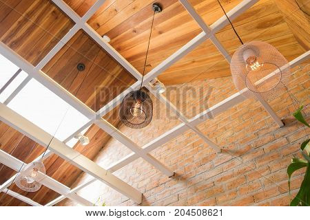 Side view of a cafe with modern black and white lamp hanging from a wooden ceiling. Brick walls style vintage in coffee shop