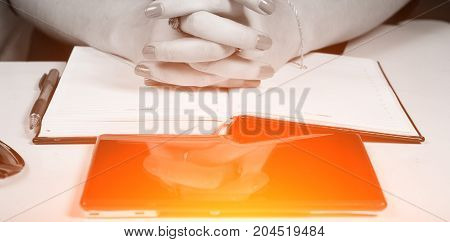Woman with folded hands sits at a Desk, a tablet and a notebook lie on the desktop, the concept of business women