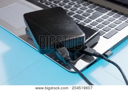Two external or portable hard drive (HDD) connected to laptop on blue table