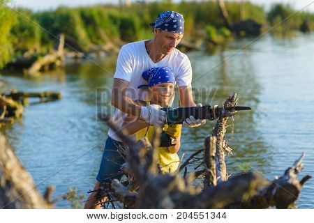 Father and Teen girl with sabersaw is sawing a logs.
