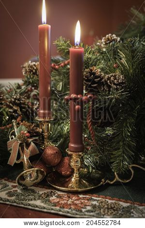Christmas tabletop decor with gold horn ornament and red candles in brass holders surrounded by greenery and pine cones