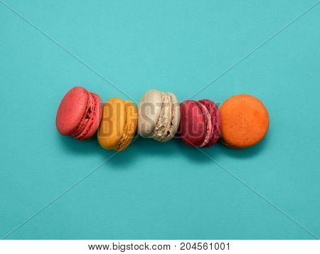Macaroons Top view Five sweet and colorful macaroons or macaron on turquoise background French dessert Trendy bright photo background with space for text