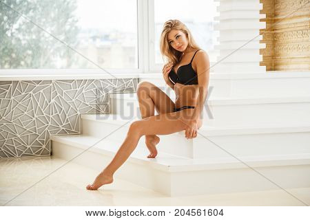 Beautiful girl blonde sexy bottom in lingerie posing in light apartments
