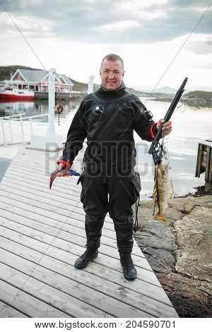 diver standing on pier with freshly caught Norwegian fishes. outdoor shot in Norway. copy space.