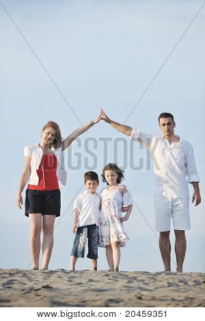 happy young family have fun on beachand showing home sign with conncected hands while protecting childrens