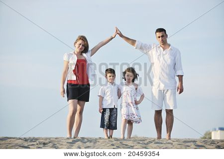 happy young family have fun on beachand showing home sign with conncected hands while protecting childrens