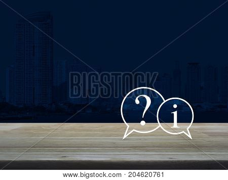 Question mark and information chat icon on wooden table over modern office city tower background Customer support concept