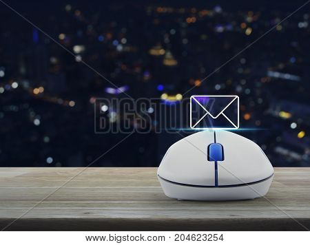 Mail flat icon with wireless computer mouse on wooden table over blur colorful night light city tower Contact us concept