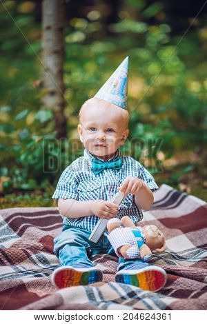 Little infant baby boy 1year kid on a plaid in park. Summer sunset. Copy space