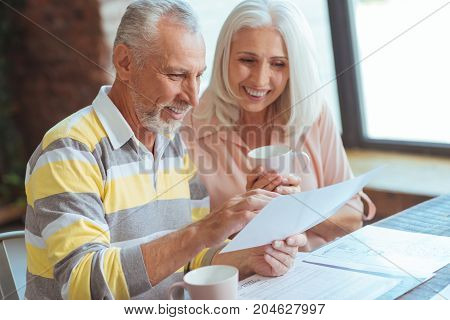 Open up the market. Positive senior couple being involved in paperwork and sitting at home while discussing their business matters