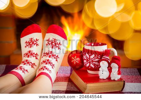 Woman in Christmas socks near fireplace. Person relaxing at home. Winter holiday Xmas and New Year concept