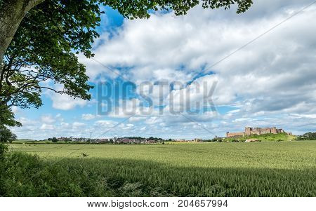 Bamburgh village and Castle, England. A view over the Northumberland countryside in north-east England towards the village of Bamburgh dominated by its famous landmark castle.