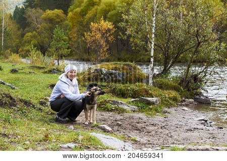 Woman with dog around Altai mountain river.
