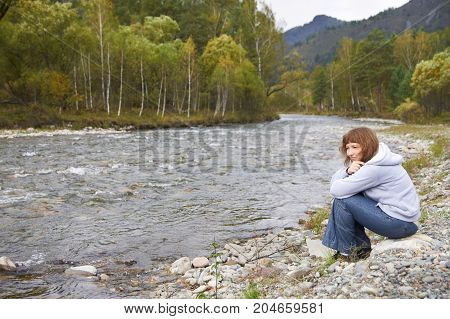 Smiling woman around Altai mountain river. Autumn.