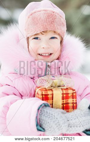 Happy smiling child with Christmas gift in winter park