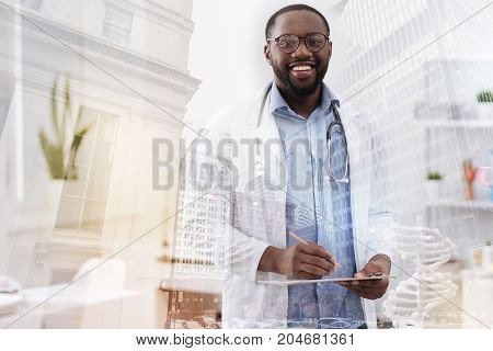 High quality service. Skilled pleasant medical worker holding notes and a pencil in the hand while expressing optimism