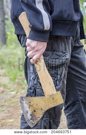 A man holds an ax in his hand while in the forest